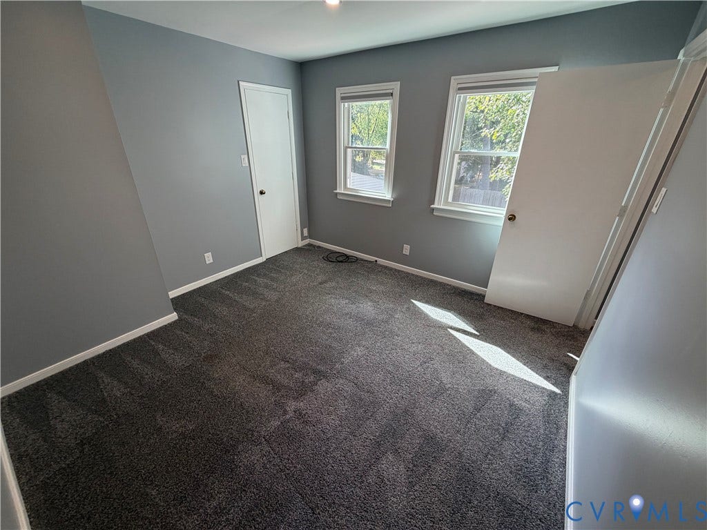 2228 Early Settlers Road, Midlothian, VA 23235 Room featuring grey wall paint, grey carpeting, two double-hung windows with white casing, and two interior doors with hardware