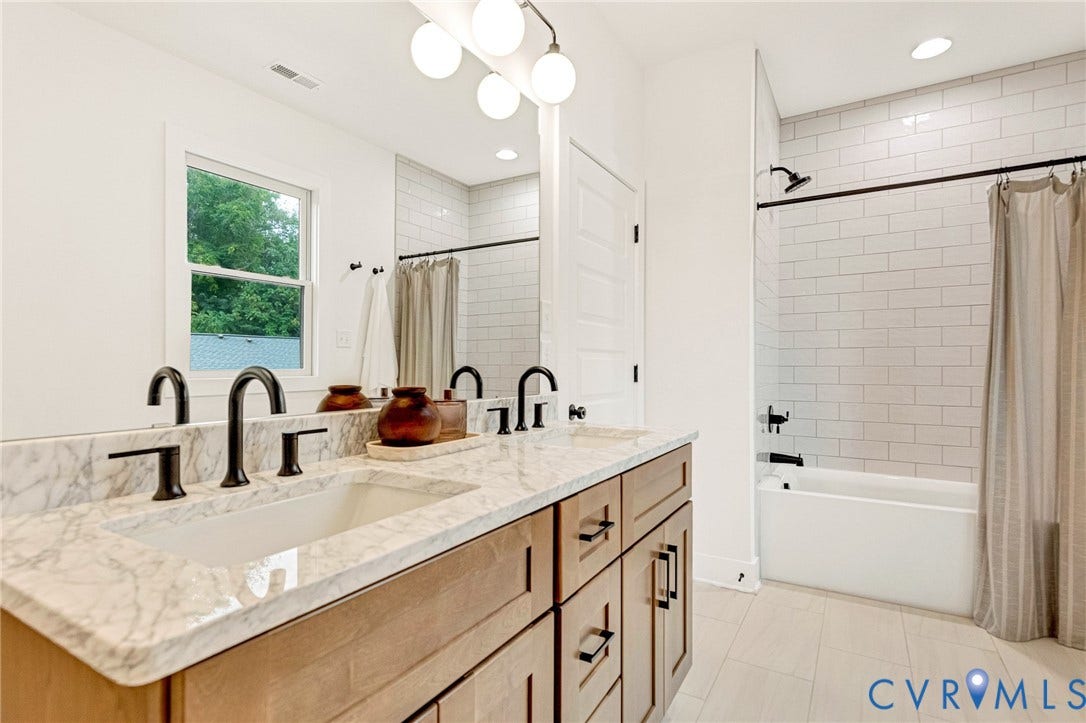 3021 E Franklin Street, St. John's Church, Richmond, VA 23223 Bathroom featuring a dual-sink vanity with stone countertop, matte black fixtures, subway tile shower surround, and globe-style vanity lighting