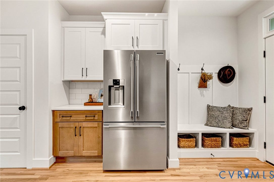 3021 E Franklin Street, St. John's Church, Richmond, VA 23223 Custom cabinetry featuring a mix of painted white upper units and wood-finish lower cabinetry, white subway tile backsplash, built-in mudroom bench with cubby storage, stainless steel French door refrigerator, and white board-and-batten wall detailing