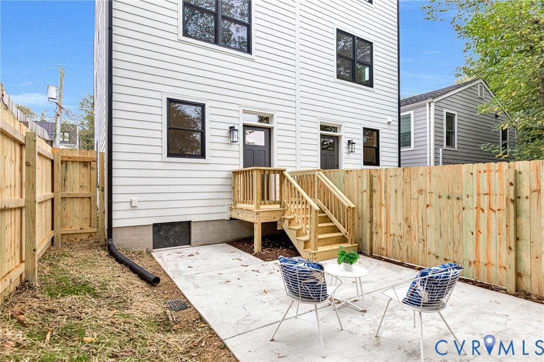3021 E Franklin Street, St. John's Church, Richmond, VA 23223 White horizontal siding exterior featuring black-framed windows, a concrete patio, wood-railing stairs, and a full-height privacy fence
