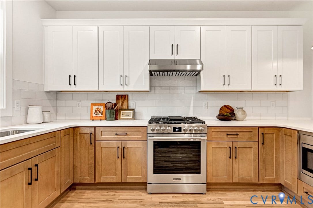 3021 E Franklin Street, St. John's Church, Richmond, VA 23223 Kitchen featuring two-tone cabinetry with white upper and light-toned lower units, subway tile backsplash, stainless steel gas range, stainless steel range hood, and solid-surface countertops