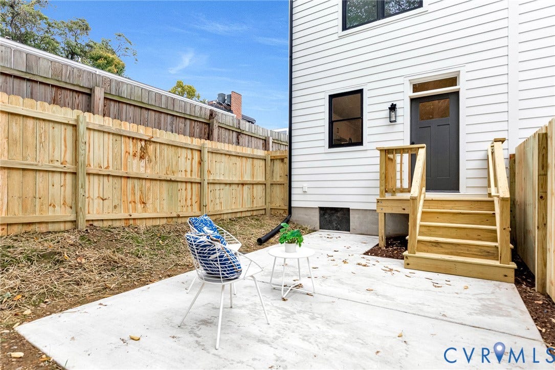 3021 E Franklin Street, St. John's Church, Richmond, VA 23223 Exterior patio featuring a concrete slab, wood privacy fencing, and a built-in wood staircase with railing leading to a dark-finished entry door