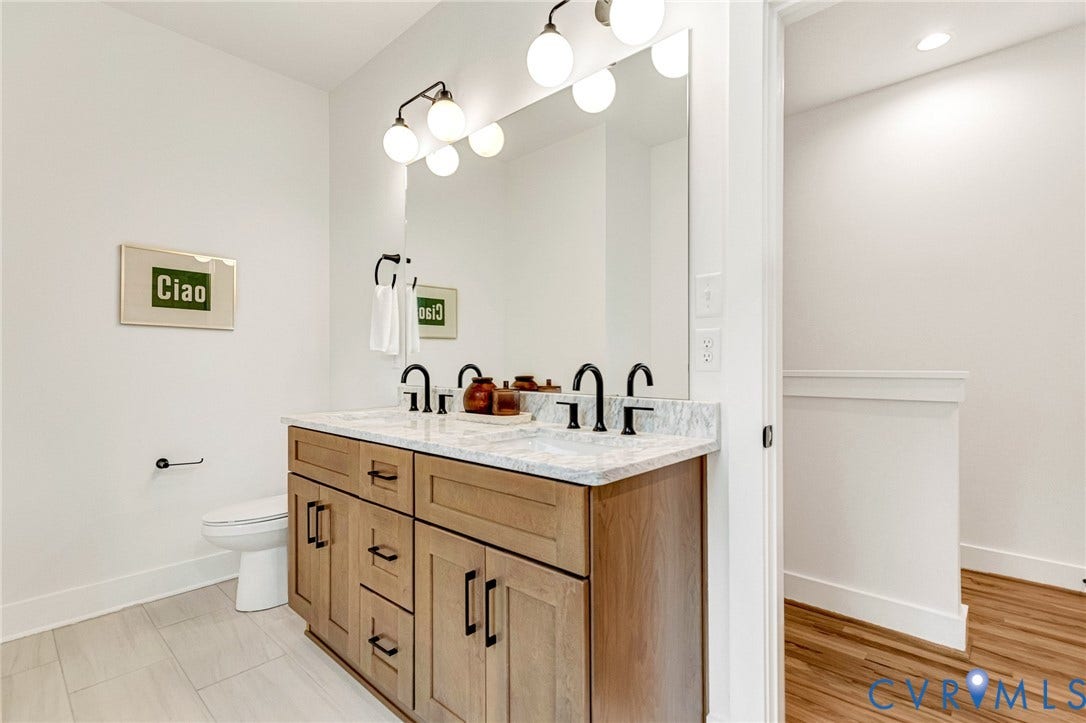 3021 E Franklin Street, St. John's Church, Richmond, VA 23223 Double vanity featuring wood-finish cabinetry, stone-patterned countertop, dual undermount sinks, matte black fixtures, and a large wall-mounted mirror
