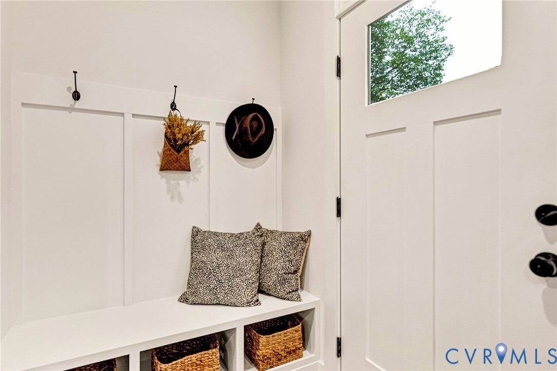 3021 E Franklin Street, St. John's Church, Richmond, VA 23223 Entryway featuring a white exterior door with a glass inlay, matte black hardware, built-in bench seating with lower storage compartments, and white board-and-batten wall detailing with mounted metal hooks