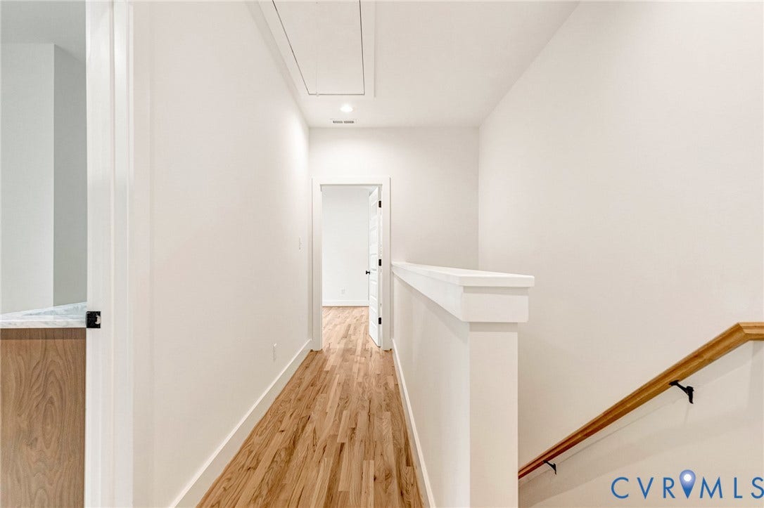 3021 E Franklin Street, St. John's Church, Richmond, VA 23223 Hallway featuring wood-finish flooring, a solid half-wall partition, and a natural wood-finish handrail with matte black hardware