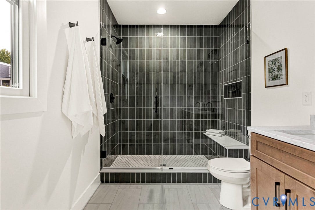 3021 E Franklin Street, St. John's Church, Richmond, VA 23223 Walk-in shower featuring vertical charcoal tile, frameless glass enclosure, built-in bench seating, recessed wall niche, and matte black plumbing fixtures