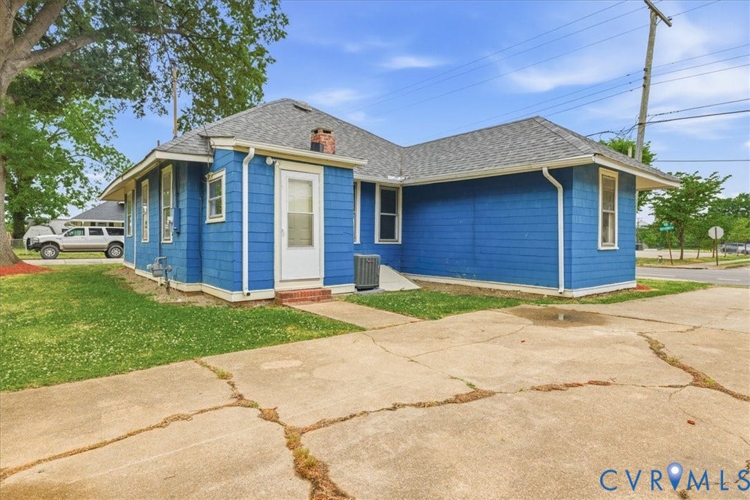 100 N 3rd Avenue, Hopewell, VA 23860 Blue-shingled exterior featuring an asphalt shingle roof, masonry chimney, and concrete surface area
