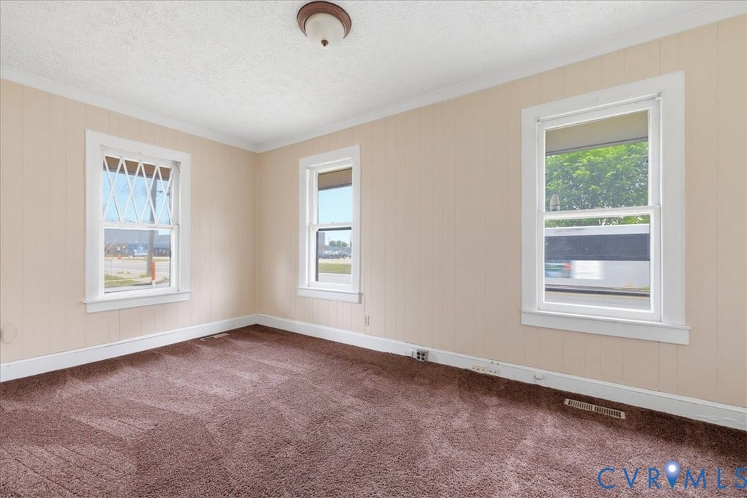 100 N 3rd Avenue, Hopewell, VA 23860 Room featuring wall-to-wall carpeting, three windows with white casing, crown molding, and a central ceiling-mounted light fixture