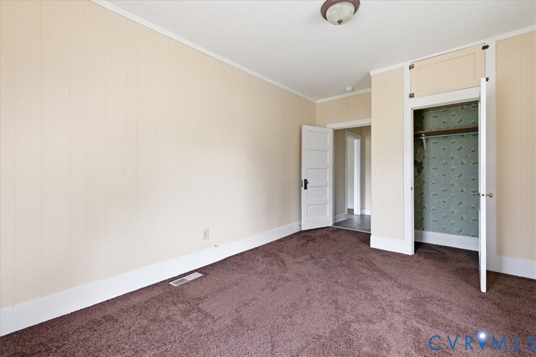 100 N 3rd Avenue, Hopewell, VA 23860 Room featuring vertical paneling, wall-to-wall carpeting, five-panel interior door, and a built-in closet with overhead storage cabinet