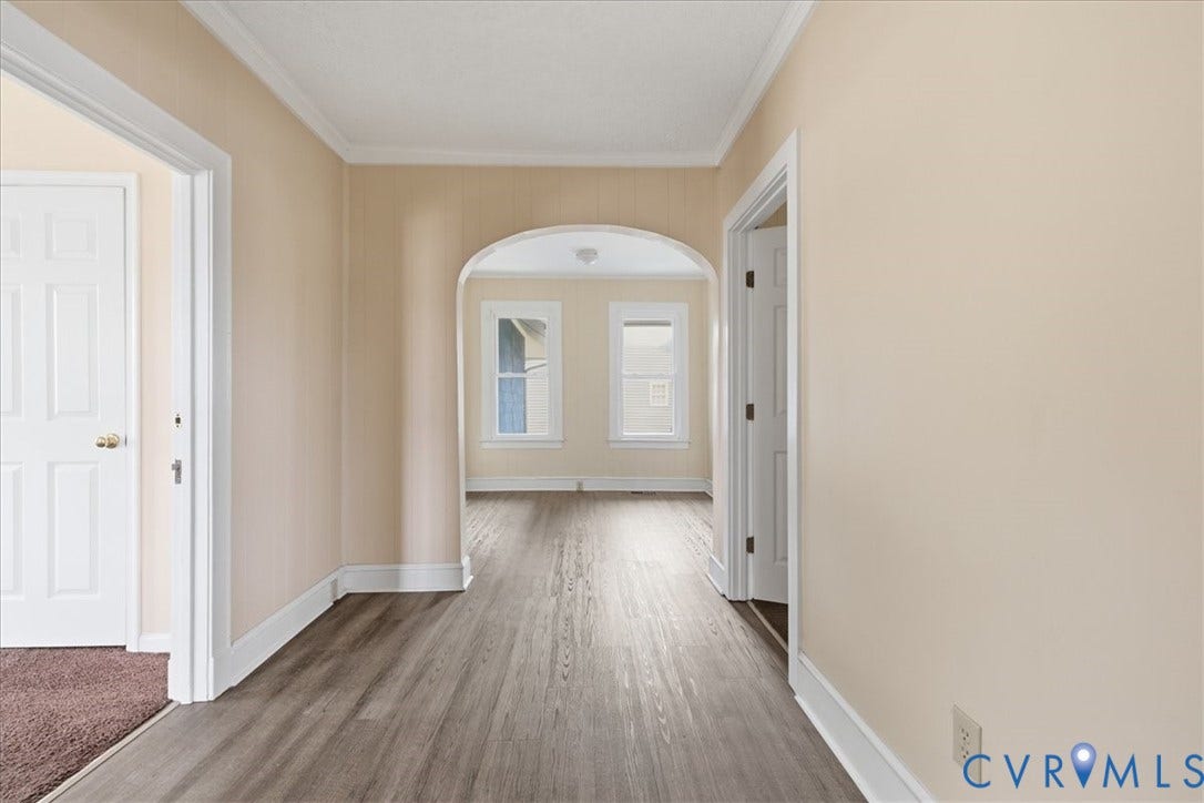 100 N 3rd Avenue, Hopewell, VA 23860 Interior hall featuring wood-finish flooring, a rounded architectural archway, neutral wall paint, and white paneled doors