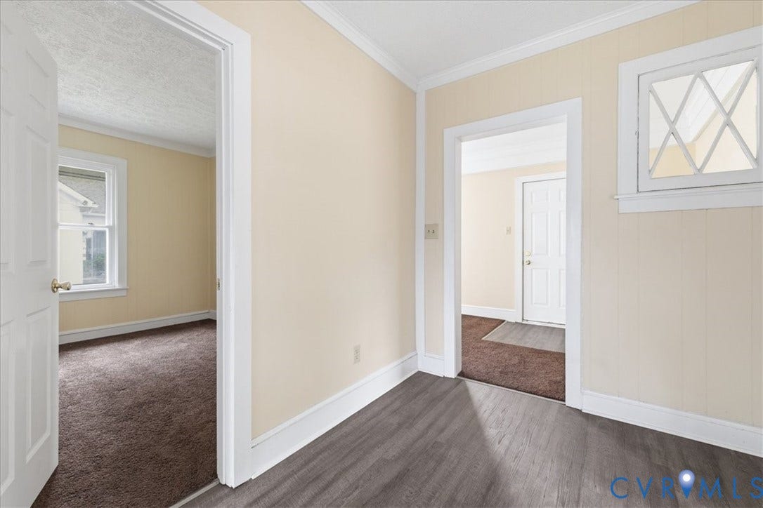 100 N 3rd Avenue, Hopewell, VA 23860 Interior area featuring light-toned wall paneling, wood-finish flooring, white crown molding, and a decorative transom window with diamond-pattern muntins