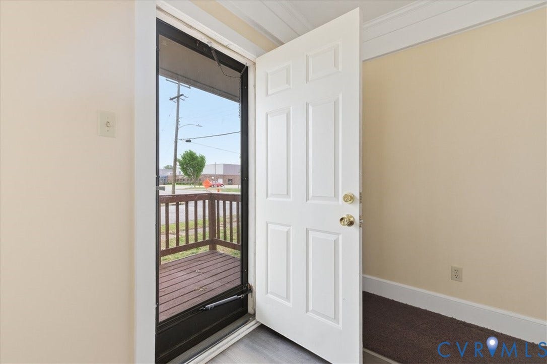 100 N 3rd Avenue, Hopewell, VA 23860 Entryway featuring a white paneled door with gold-tone hardware, a screen door, and an exterior wood-decking porch