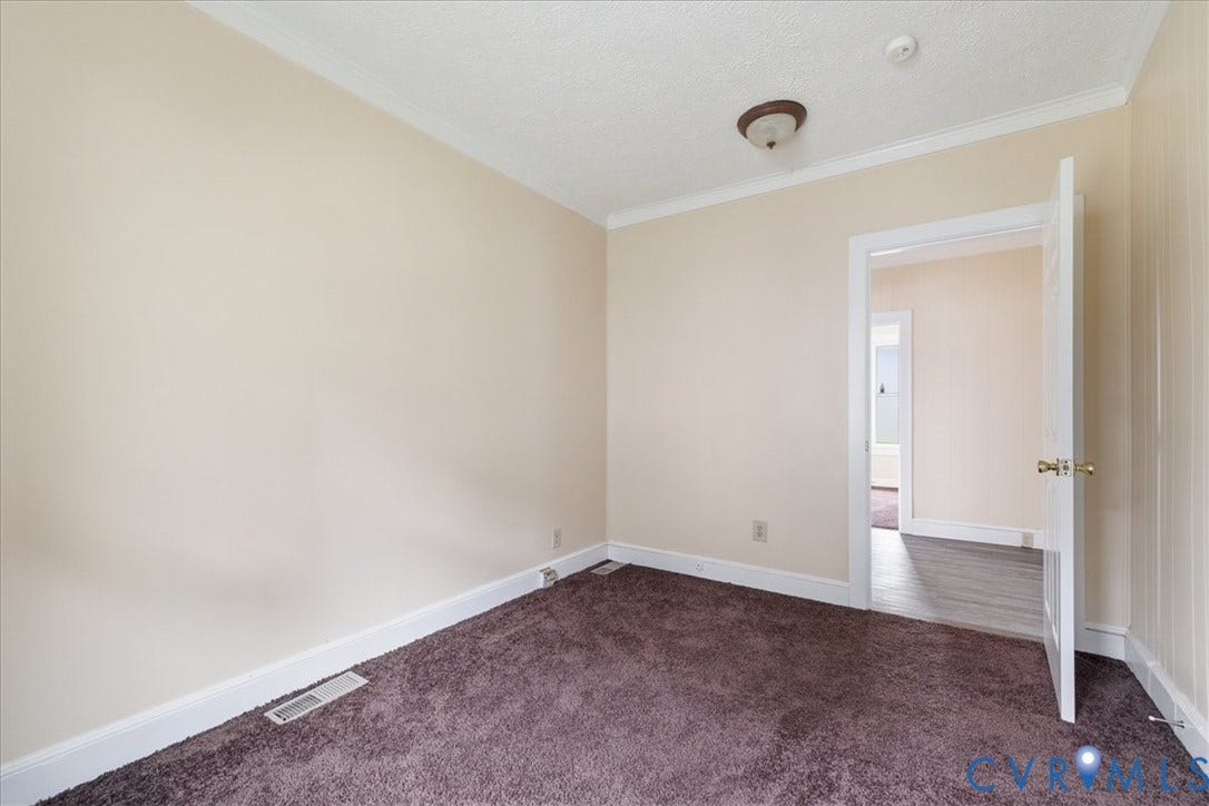100 N 3rd Avenue, Hopewell, VA 23860 Neutral-toned walls paired with crown molding, plush wall-to-wall carpeting, and a central ceiling-mounted light fixture