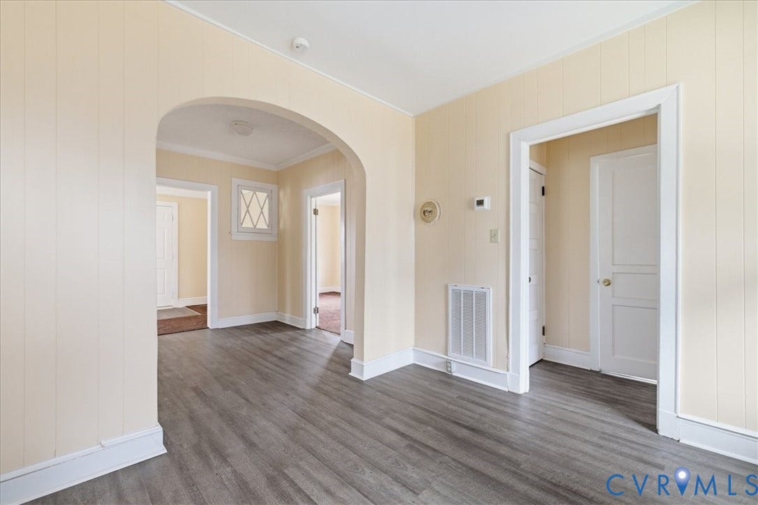 100 N 3rd Avenue, Hopewell, VA 23860 Interior space featuring wood-finish flooring, vertical panel wall detailing, and a prominent arched entryway