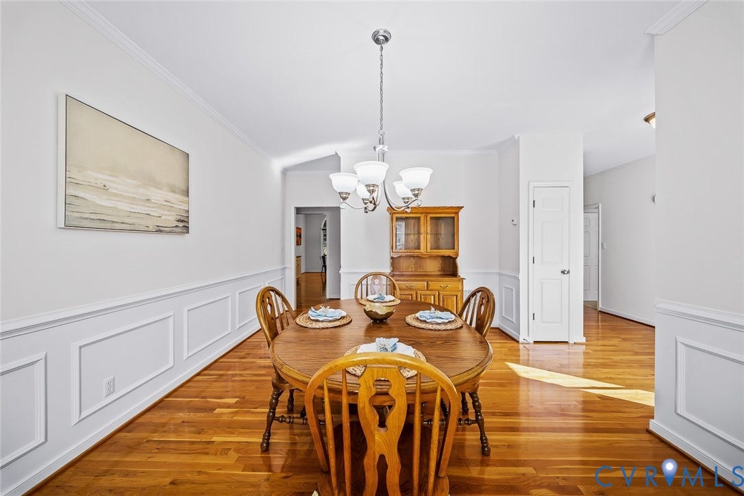 Dining area featuring hard wood flooring, white wainscoting, and a central five-light chandelier