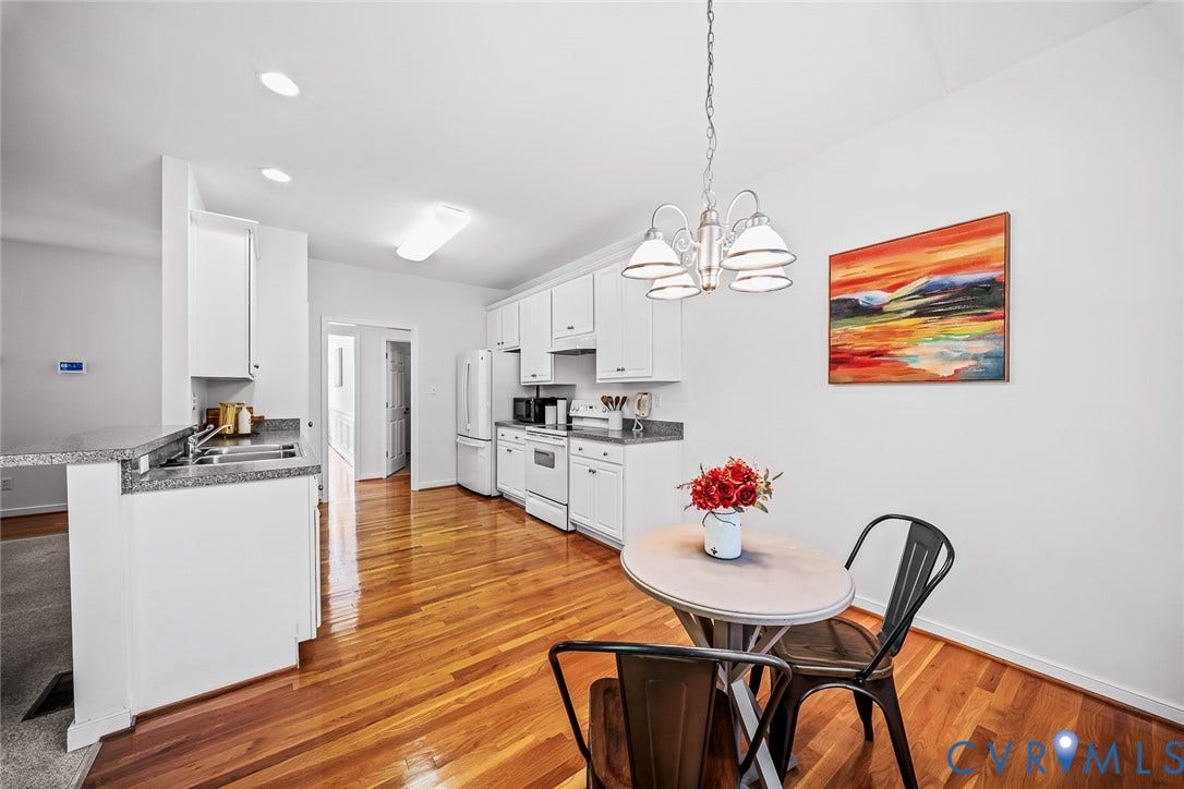 Vaulted ceiling with an arched window, hard wood flooring, and eat-in area