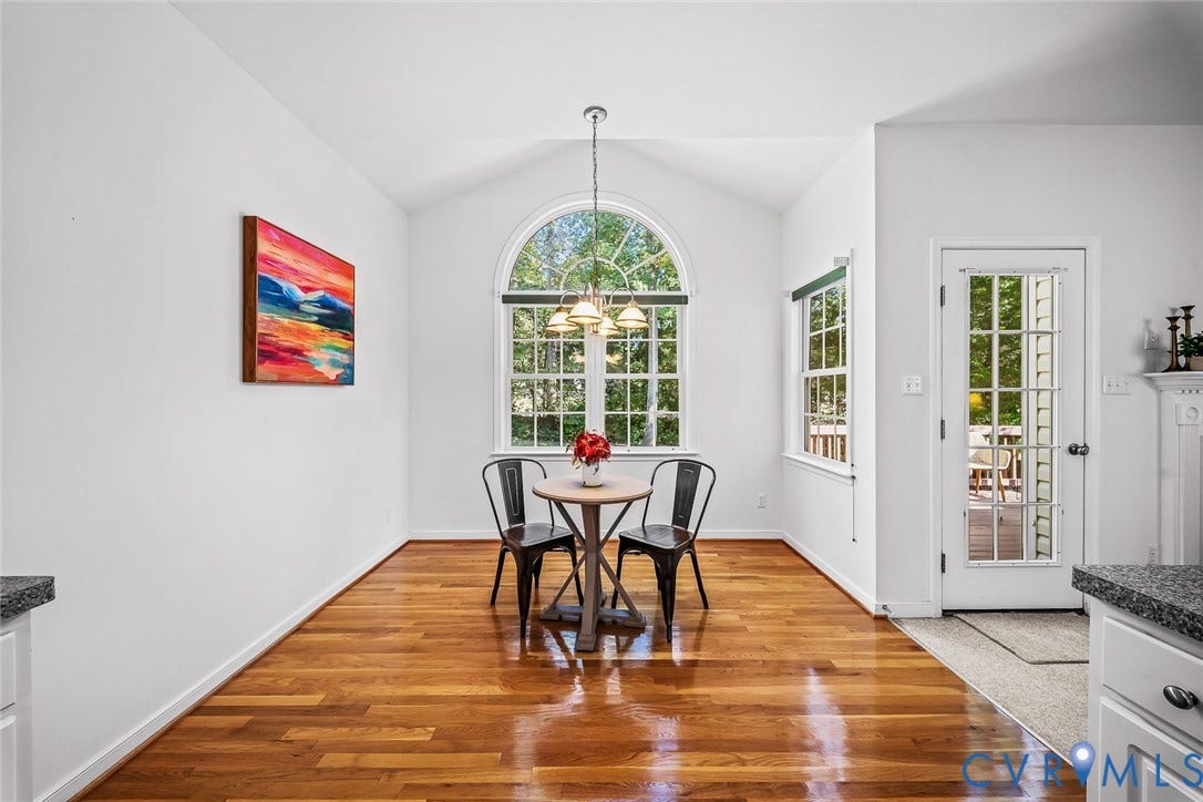 Vaulted ceiling with an arched window, hard wood flooring, and eat-in area