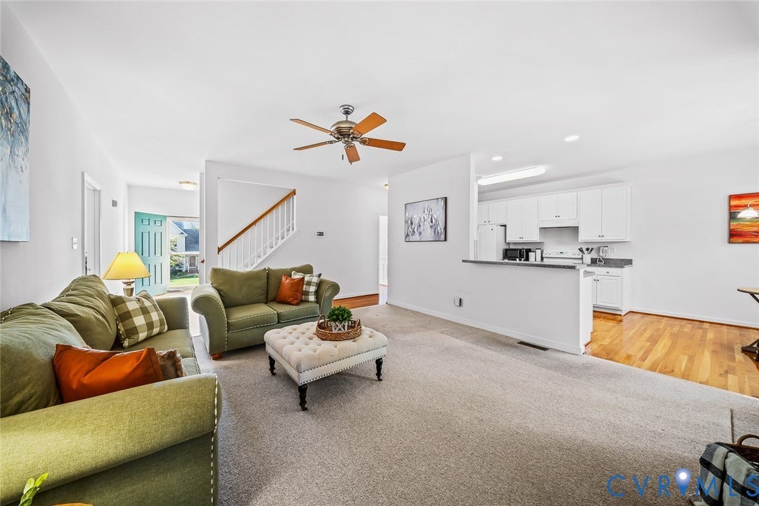 Living area featuring a fireplace with a recessed hearth, arched window, dual glass-paned exterior doors, and a ceiling fan