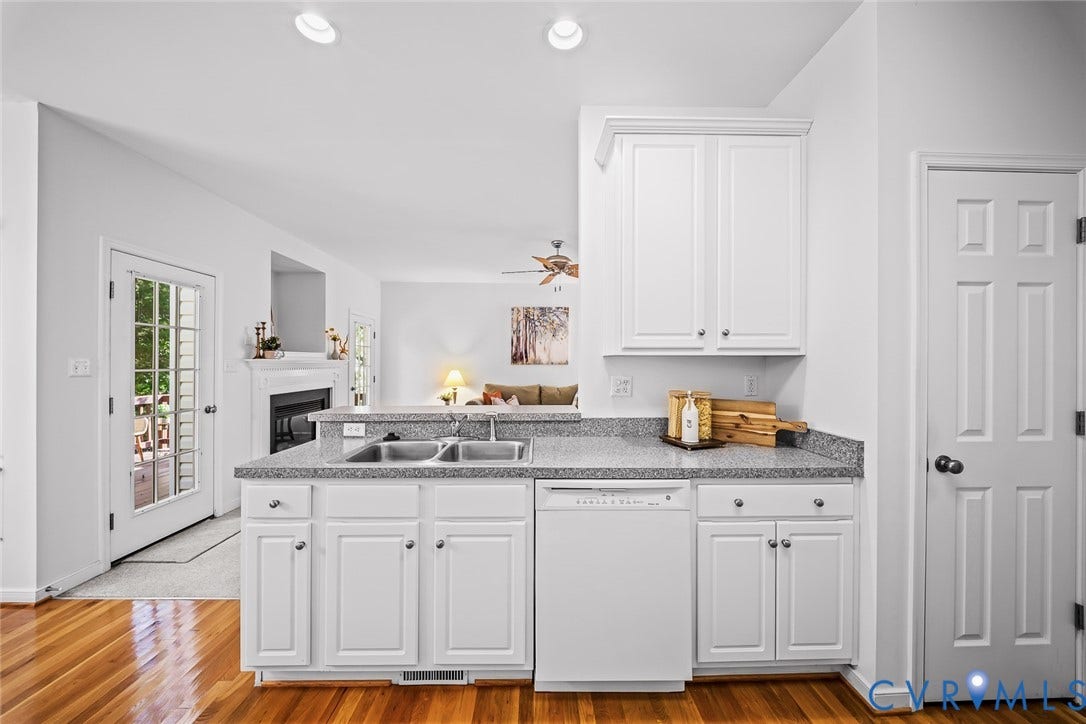 Kitchen featuring white shaker-style cabinetry, hard wood flooring, and a pantry