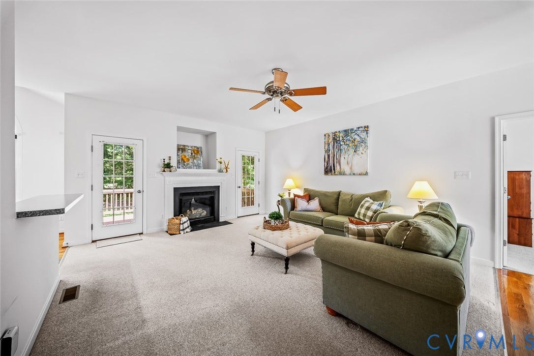 Living area featuring a fireplace with a mantel, built-in recessed niche, ceiling fan, and double glass-paneled exterior doors