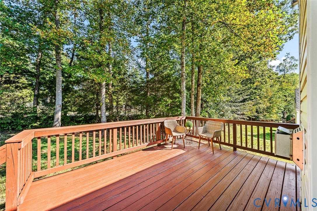 Elevated wood deck featuring vertical slat railing and surrounding mature forest canopy