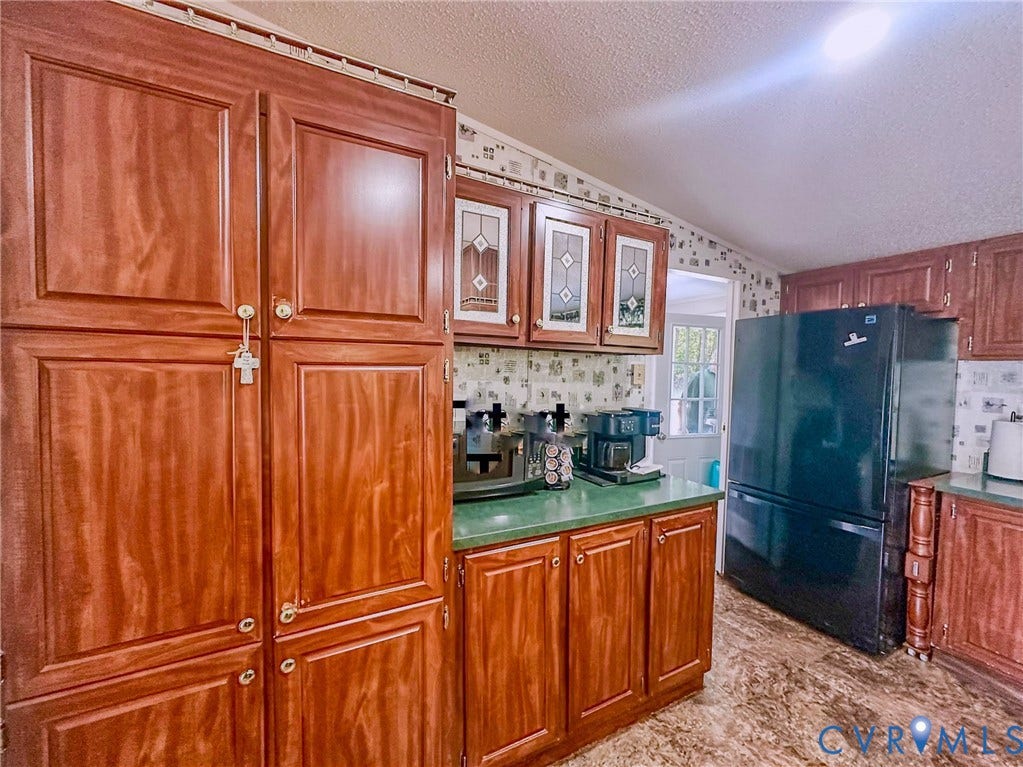 25400 SAYLERS CREEK ROAD, Deatonville, Jetersville, VA 23083 Kitchen featuring wood cabinetry with upper glass-panel inserts, solid-surface countertops, and a full-height refrigerator