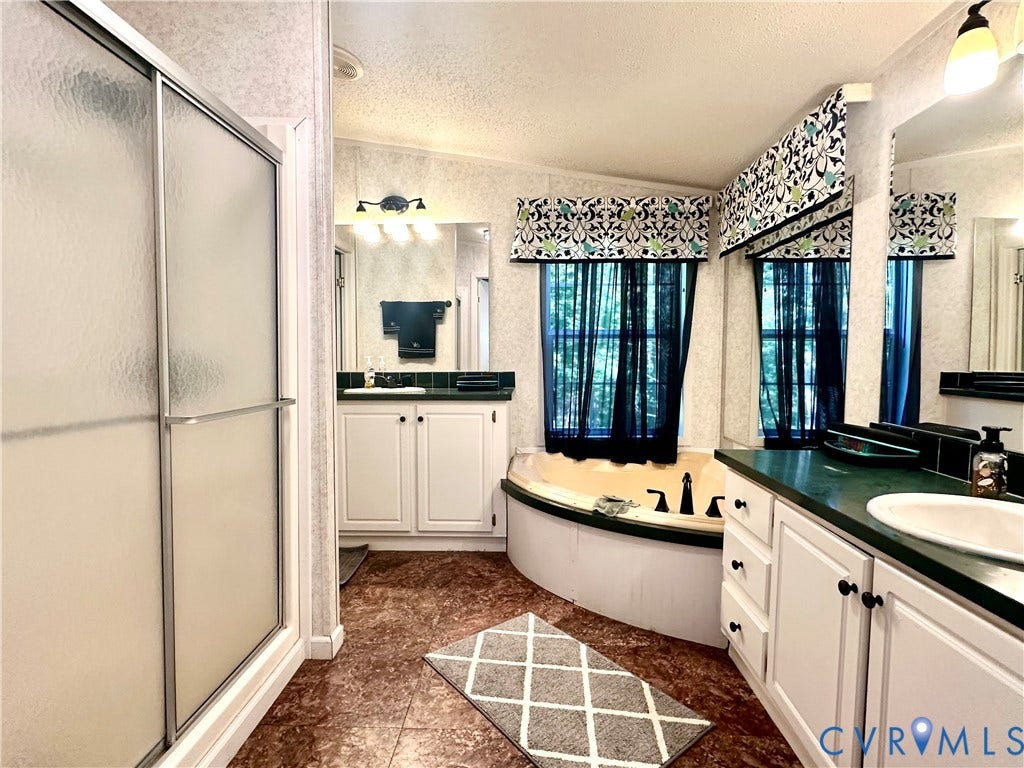 25400 SAYLERS CREEK ROAD, Deatonville, Jetersville, VA 23083 Bathroom featuring a corner soaking tub, a separate walk-in shower with frosted glass doors, dual white cabinetry vanities, and contrasting dark countertops