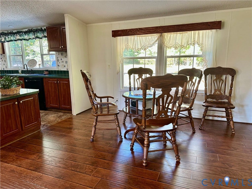 25400 SAYLERS CREEK ROAD, Deatonville, Jetersville, VA 23083 Kitchen featuring wood-finish cabinetry, countertop with integrated backsplash, wood-finish flooring, and large windows with decorative wood trim
