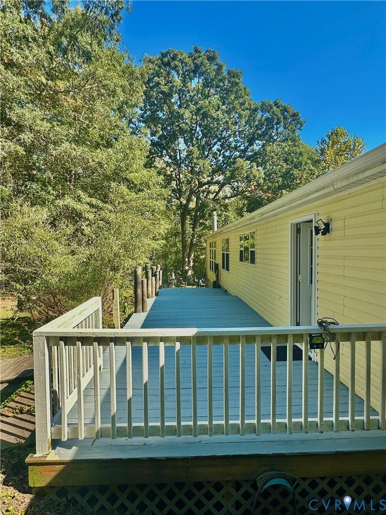 25400 SAYLERS CREEK ROAD, Deatonville, Jetersville, VA 23083 Extended exterior wood decking featuring a white railing, lattice skirting, and mature tree canopy