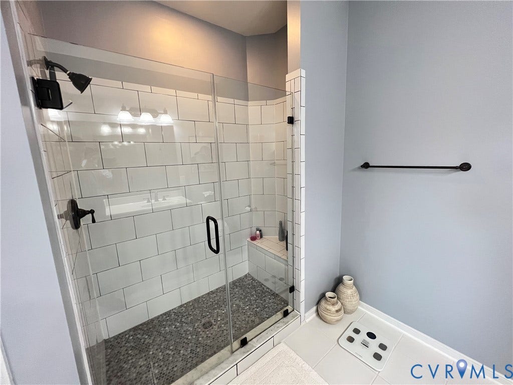 2310 Liesfeld Parkway, West Broad Village, Henrico, VA 23060 Walk-in shower featuring a glass enclosure, white subway tile surround, pebble-style floor tiling, built-in corner bench, and matte black fixtures