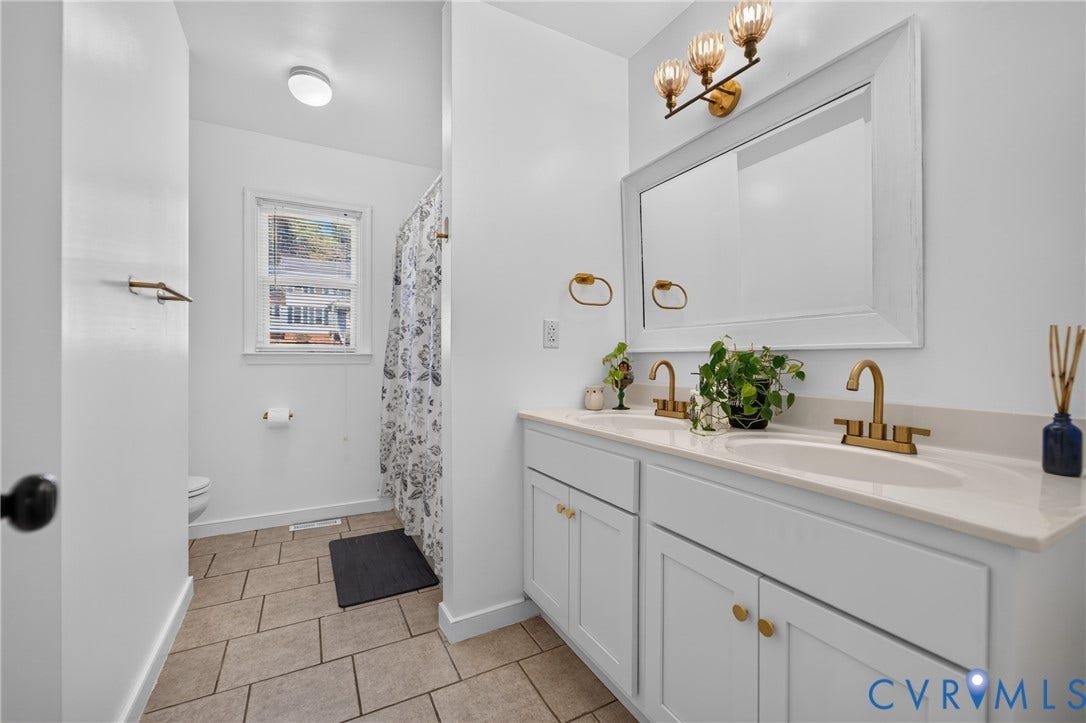 7225 Hartsdale Court, Chesterfield, VA 23832 Dual-sink vanity with neutral countertop, brass-finish fixtures, wall-mounted mirror, and tile flooring