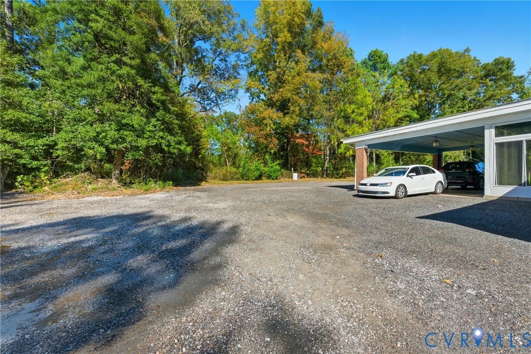 13225 Old Happy Hill Road, Chester, VA 23831 Covered carport with brick support columns, expansive gravel parking area, and mature perimeter trees