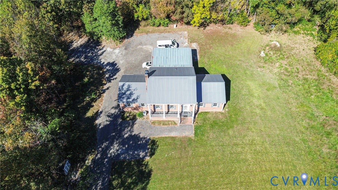 13225 Old Happy Hill Road, Chester, VA 23831 Aerial perspective of a brick residence featuring a metal roof, a front-facing porch, a gravel driveway, and a partially wooded lot