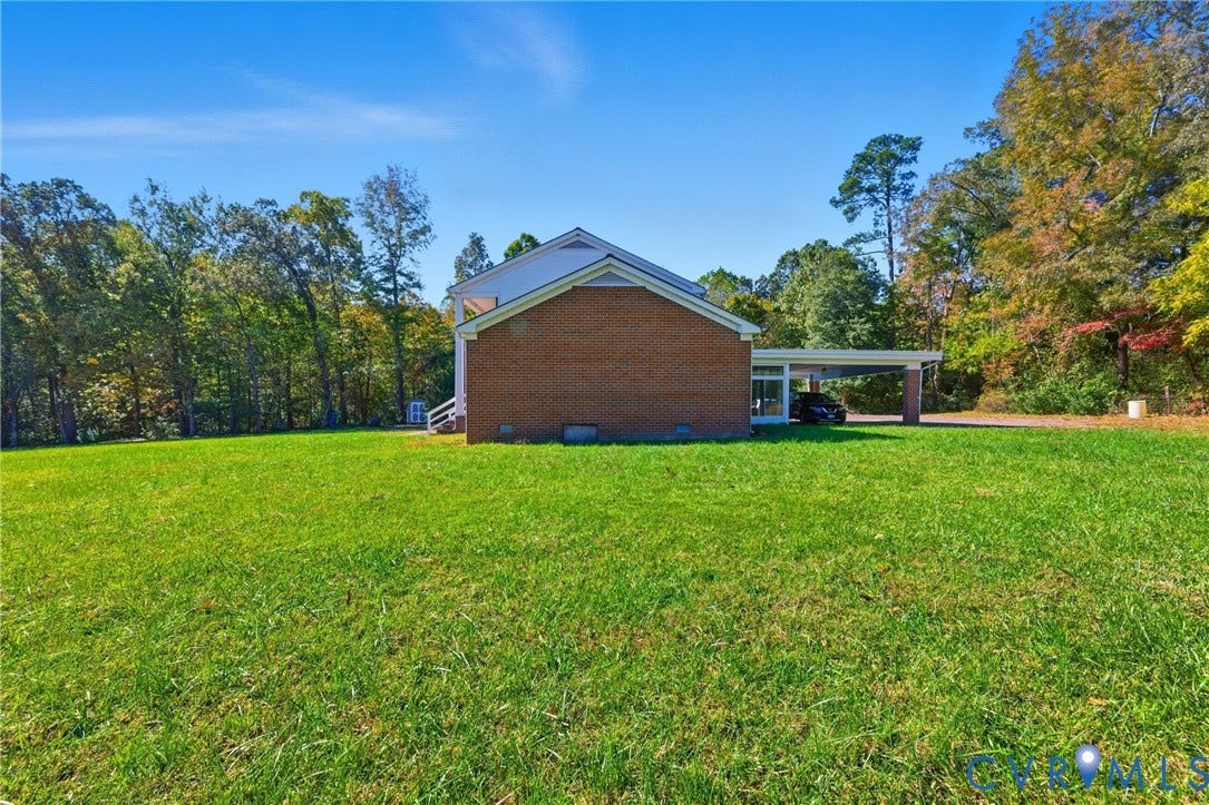 13225 Old Happy Hill Road, Chester, VA 23831 Brick exterior residence featuring an expansive lawn, attached carport, and mature perimeter trees