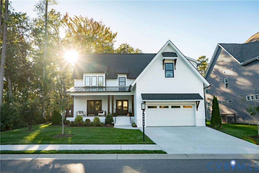 6020 Rivermere Lane, Glen Allen, VA 23059 White Brick exterior featuring horizontal siding, a covered front porch with dark timber posts, a metal roof accent, a two-car garage, and steep roof gables
