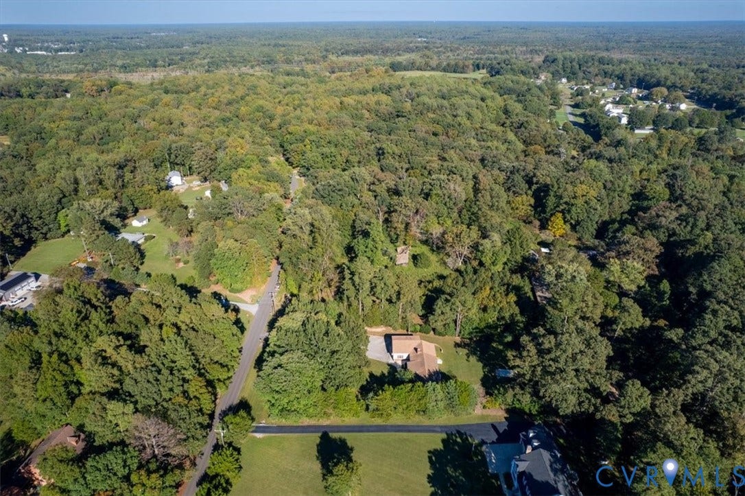 5111 Hurop Road, Sandston, VA 23150 Aerial view of a sprawling lot featuring dense mature forest coverage, expansive cleared acreage, and paved road access