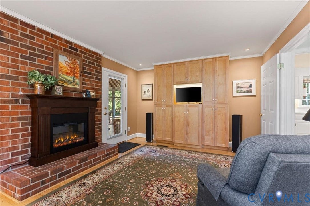 5111 Hurop Road, Sandston, VA 23150 Exposed brick wall featuring an integrated fireplace with a wood mantle, custom floor-to-ceiling cabinetry, and a glass-paneled exterior door