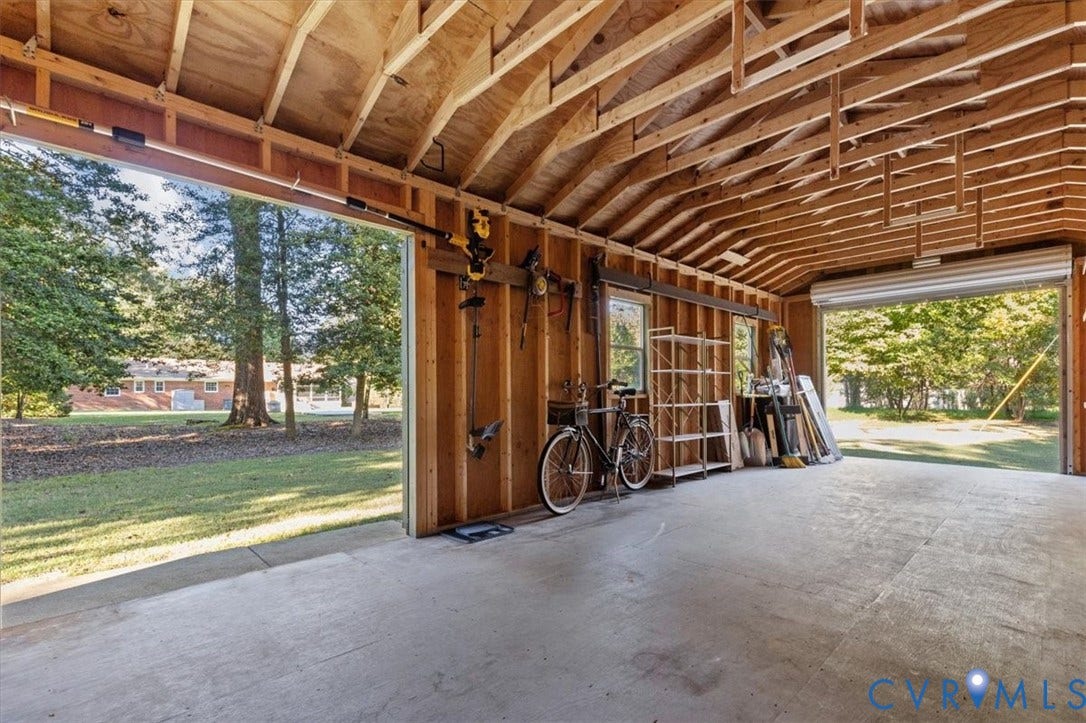5111 Hurop Road, Sandston, VA 23150 Multi-bay garage with exposed rafter ceiling, concrete flooring, dual overhead doors, and natural light