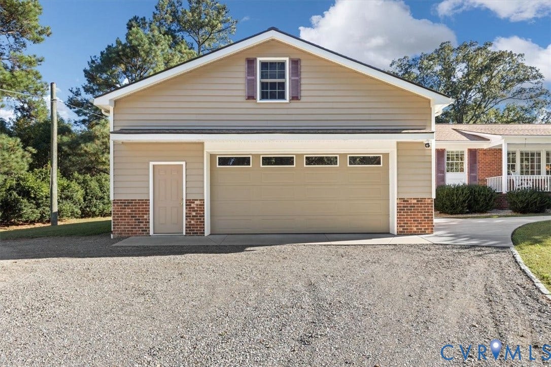 5111 Hurop Road, Sandston, VA 23150 Detached garage featuring horizontal siding, brick masonry detailing, a multi-panel overhead door with inset windows, and an upper-level gable window