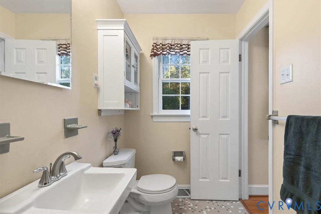 5111 Hurop Road, Sandston, VA 23150 Wall-mounted white cabinetry, sink with chrome finish faucet, single-hung window, six-panel interior door, and mosaic tile flooring