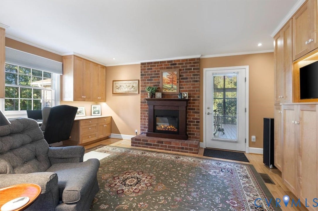 5111 Hurop Road, Sandston, VA 23150 Exposed red brick fireplace with dark wood mantel, custom light wood built-in cabinetry, wood-finish flooring, and recessed lighting