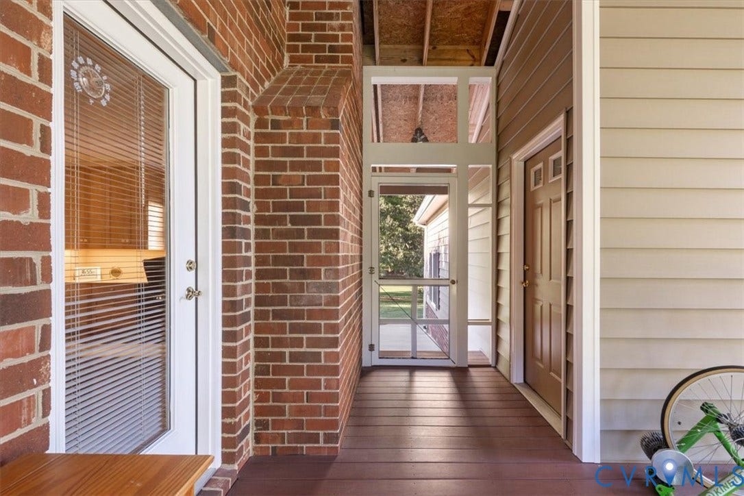 5111 Hurop Road, Sandston, VA 23150 Covered patio featuring red brick masonry, composite wood-finish decking, horizontal lap siding, and a screened door entry