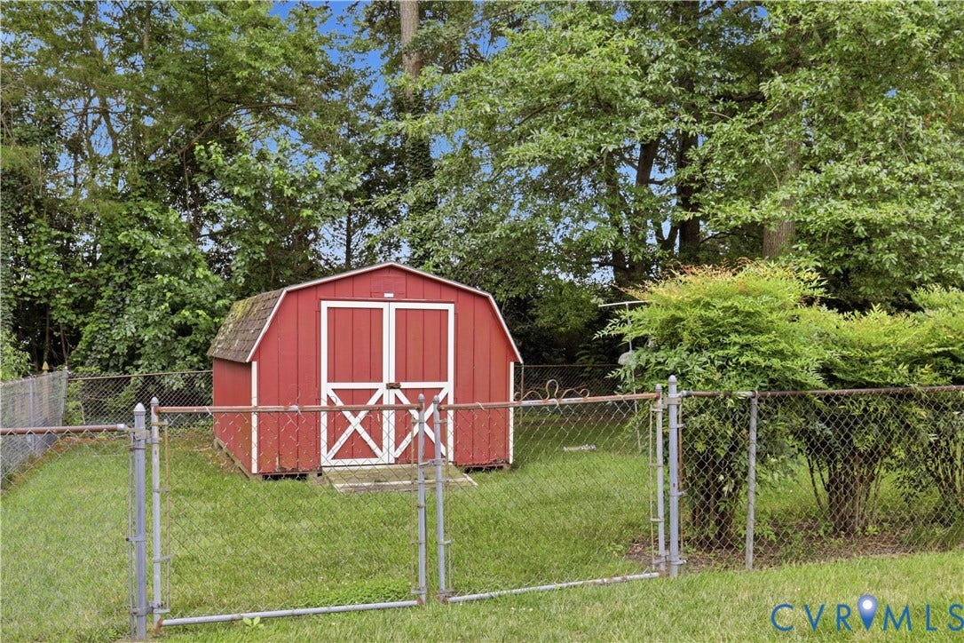 3641 Kiefer Road, Bermuda, Chester, VA 23831 Gambrel-roof storage shed featuring painted red wood siding, white trim, double-door entry, and a chain-link fenced perimeter