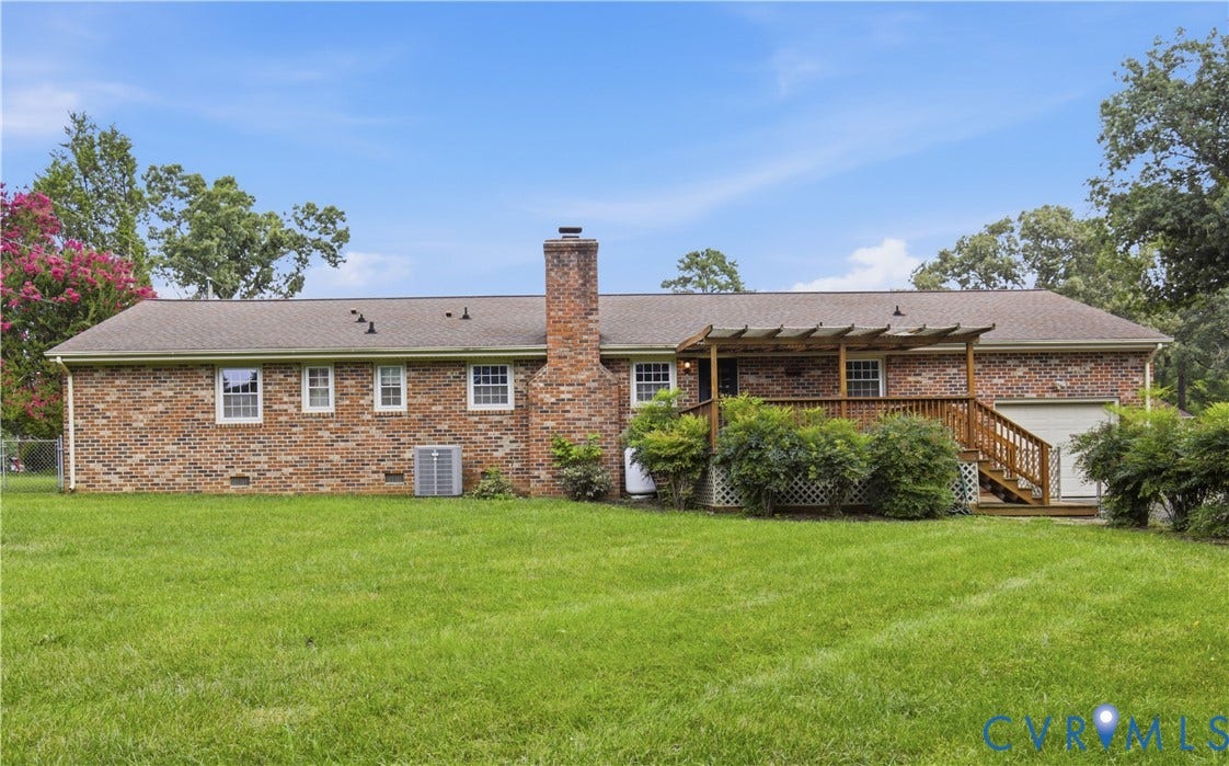 3641 Kiefer Road, Bermuda, Chester, VA 23831 Brick exterior featuring a central masonry chimney, a raised wooden deck with pergola, and expansive lawn
