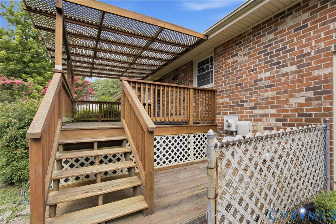 3641 Kiefer Road, Bermuda, Chester, VA 23831 Exterior elevated wood deck featuring a lattice-covered pergola, wooden railings, and lattice skirting, set against a brick facade