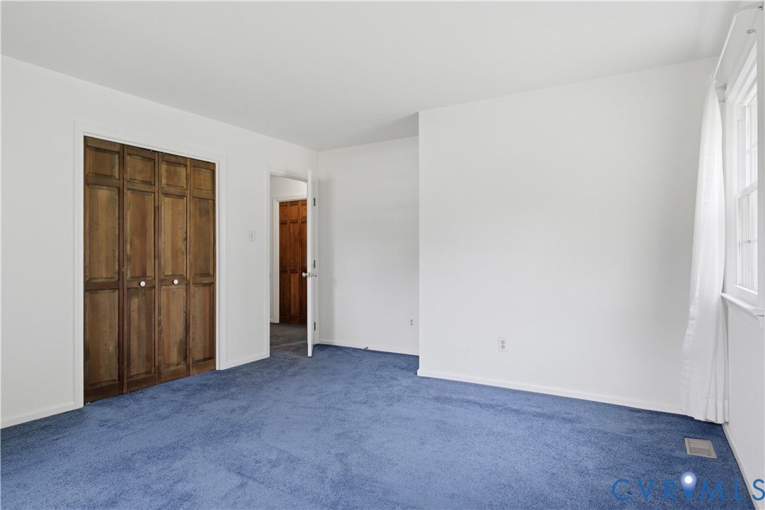 3641 Kiefer Road, Bermuda, Chester, VA 23831 Interior space featuring neutral wall tones, blue wall-to-wall carpeting, wood-finish bifold closet doors, and a multi-pane window
