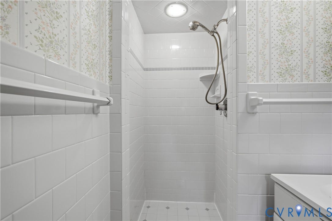 3641 Kiefer Road, Bermuda, Chester, VA 23831 Shower enclosure featuring white subway tile wall surround, built-in shelving, handheld shower fixture, and square floor tiling with accent detailing