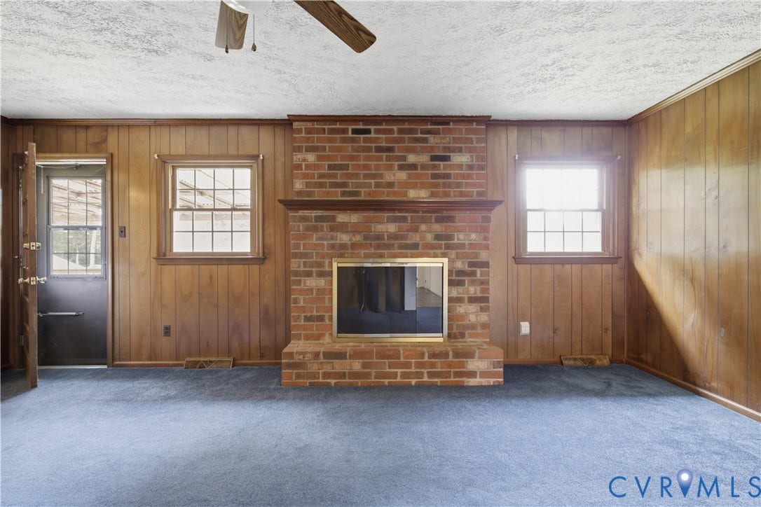 3641 Kiefer Road, Bermuda, Chester, VA 23831 Center fireplace with a brick surround, wood-finish wall paneling, dual window casings, and a ceiling-mounted fan