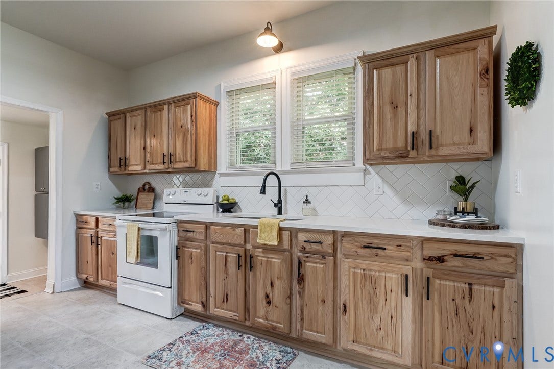 Kitchen featuring custom wood cabinetry, white countertops, herringbone-patterned tile backsplash, matte black hardware, and a single-handle pull-down faucet