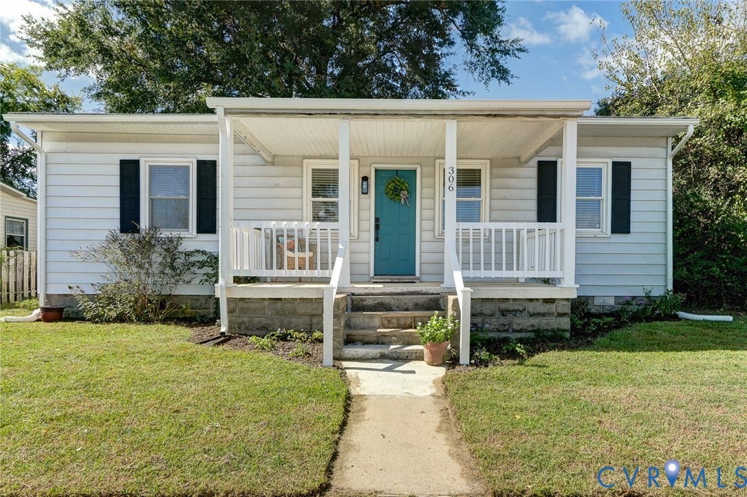 Single-story exterior featuring white horizontal siding, a covered front porch with white railing, and a stone foundation